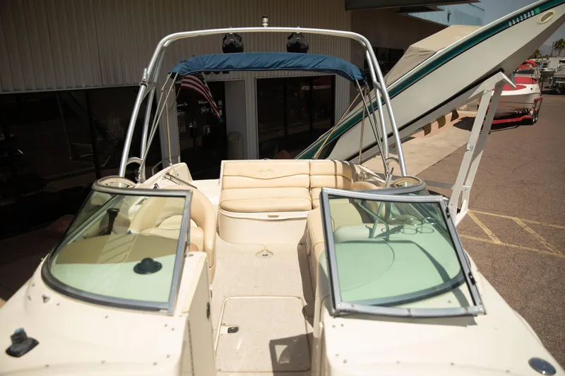 Slide: The Image of 2002 Sea Ray 240 Sundeck boat with open seating and windshield, parked outdoors. - 7