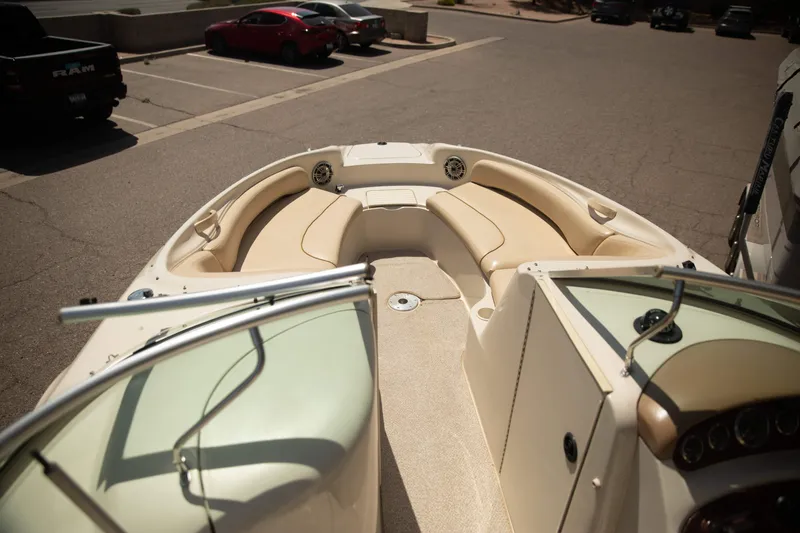 Slide: The Image of 2002 Sea Ray 240 Sundeck boat interior with beige seating in a parking lot. - 8