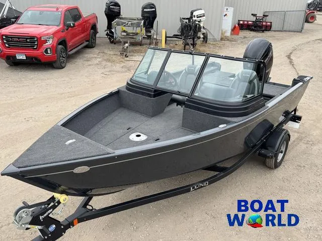 Slide: The Image of 2021 Lund 1675 Adventure Sport boat on trailer, parked near red truck and outboard motors. - 4
