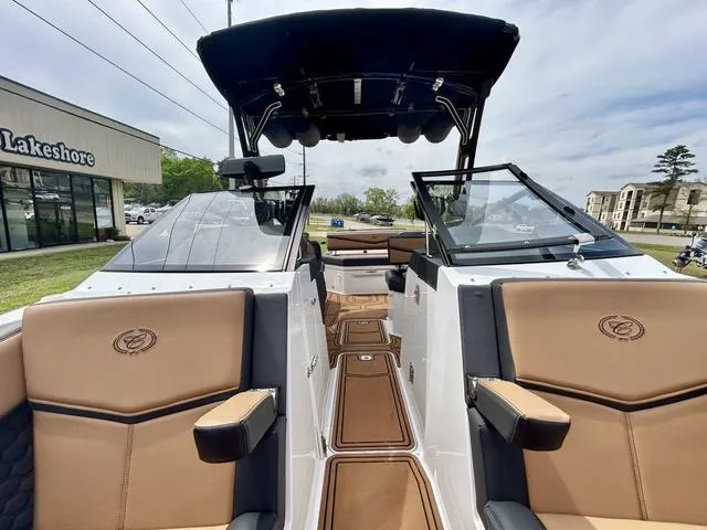 Slide: The Image of 2023 Cobalt R6 Surf boat with tan seating and black canopy, displayed outdoors. - 16