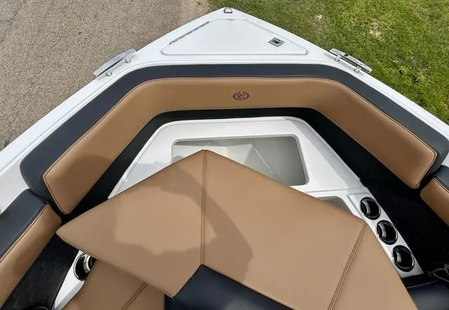 Slide: The Image of 2023 Cobalt R6 Surf boat interior with tan and black seating, cup holders, and storage compartment. - 21