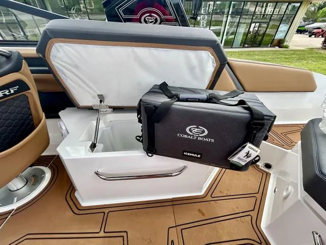 Slide: The Image of 2023 Cobalt R6 Surf boat interior with storage compartment and branded cooler. - 46