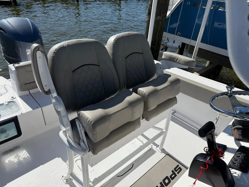 Slide: The Image of 2024 Sportsman Heritage 231 Center Console boat seats with steering wheel, docked by water. - 10