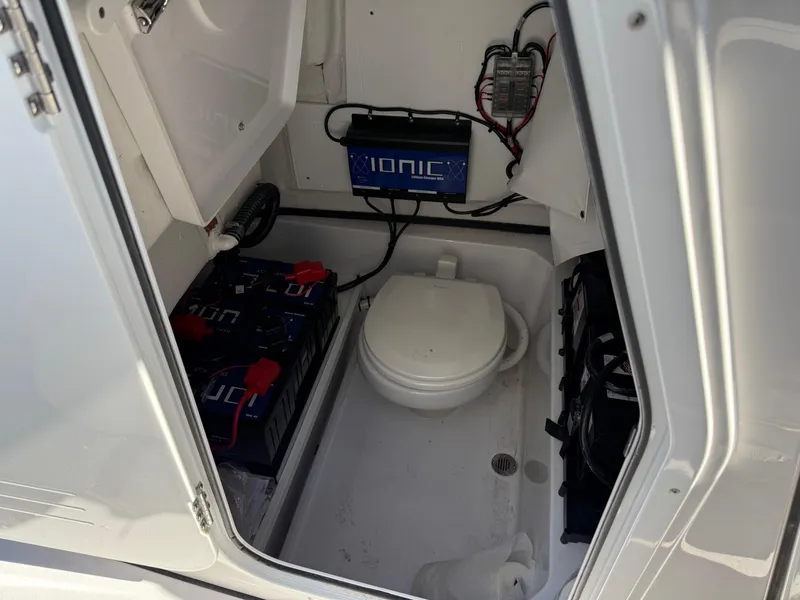 Slide: The Image of 2024 Sportsman Heritage 231 Center Console boat interior with toilet and battery setup. - 15