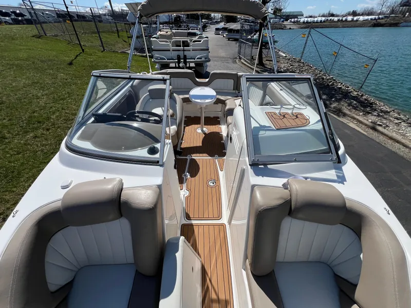 Slide: The Image of 2008 Yamaha Boats 232 Limited interior with seating, steering, and table, docked by a lake. - 20