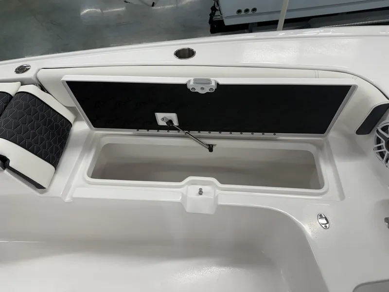 Slide: The Image of 2025 Tidewater 3100 Carolina Bay boat storage compartment with cushioned seating and speaker. - 13