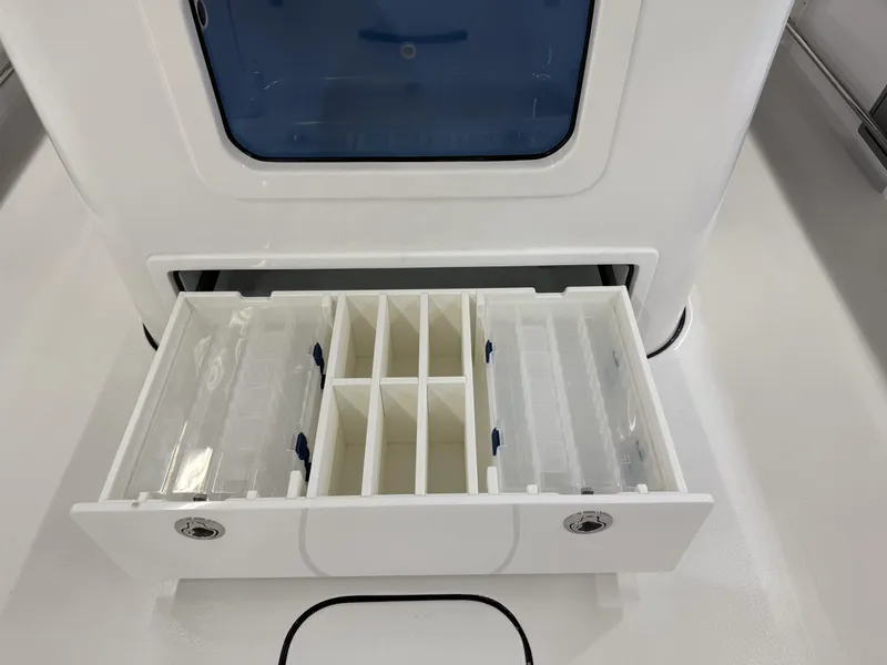 Slide: The Image of Tidewater 3100 Carolina Bay 2025 boat storage compartment with organized tackle trays. - 9