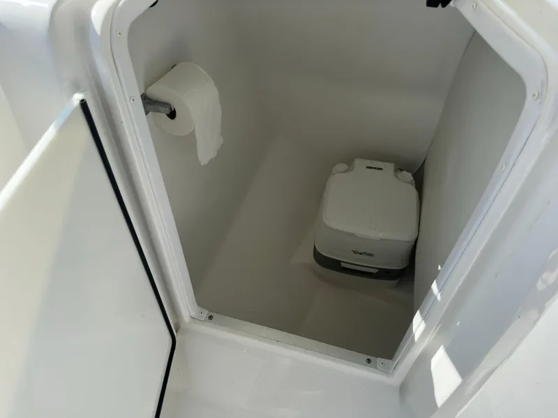 Slide: The Image of 2022 Hurricane SunDeck 235 OB boat toilet compartment with portable toilet and toilet paper. - 23