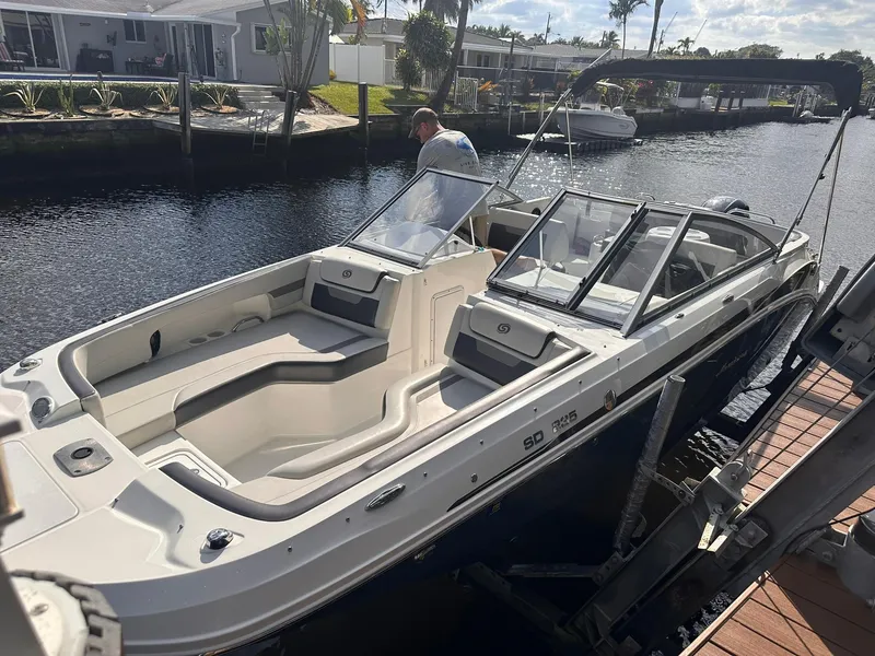 Slide: The Image of 2022 Hurricane SunDeck 235 OB boat docked by a canal, featuring spacious seating and sleek design. - 27