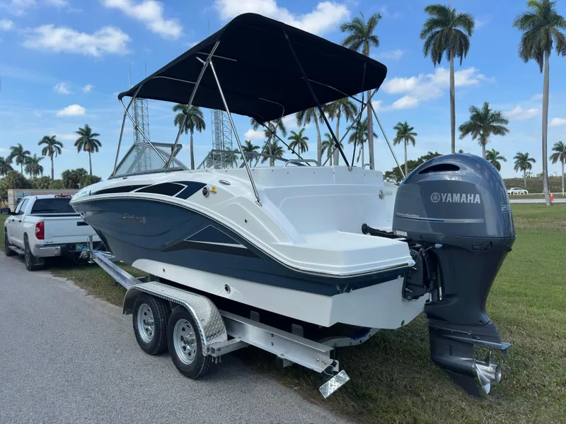 Slide: The Image of 2022 Hurricane SunDeck 235 OB boat on trailer with Yamaha outboard, parked near palm trees. - 5