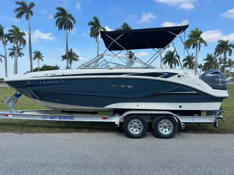 Slide: The Image of 2022 Hurricane SunDeck 235 OB boat on trailer, palm trees in background. - 6