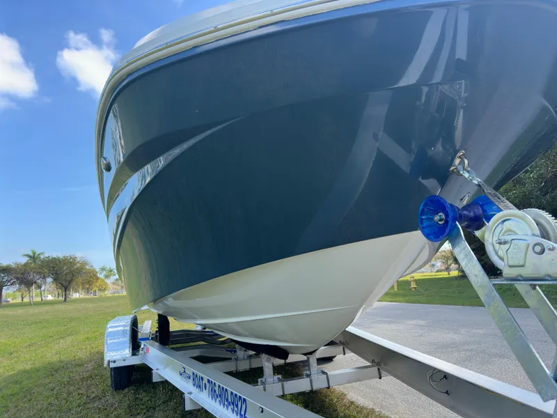 Slide: The Image of 2022 Hurricane SunDeck 235 OB boat on trailer, parked on grass under blue sky. - 9