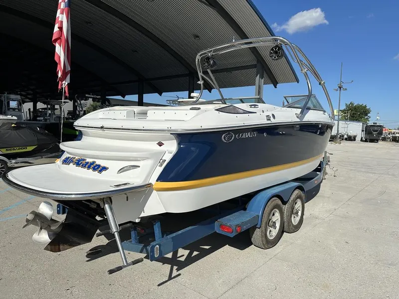 Slide: The Image of 2006 Cobalt 250 boat on trailer, parked outdoors under a canopy, with American flag nearby. - 11