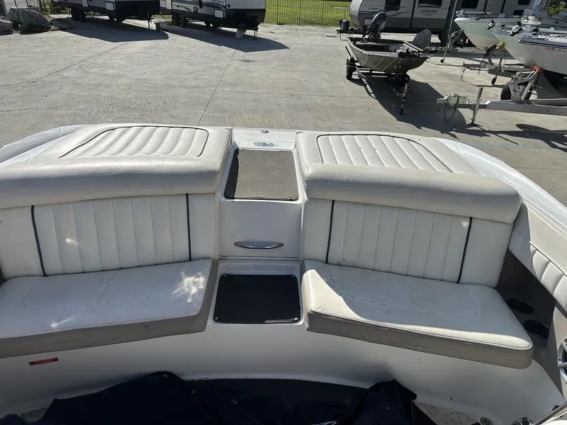 Slide: The Image of 2006 Cobalt 250 boat interior with white cushioned seating in a parking area. - 8