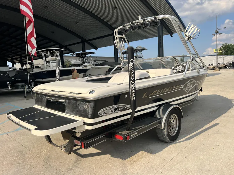 Slide: The Image of 2003 Supra Launch LTS boat on trailer, parked under a canopy with other boats. - 12