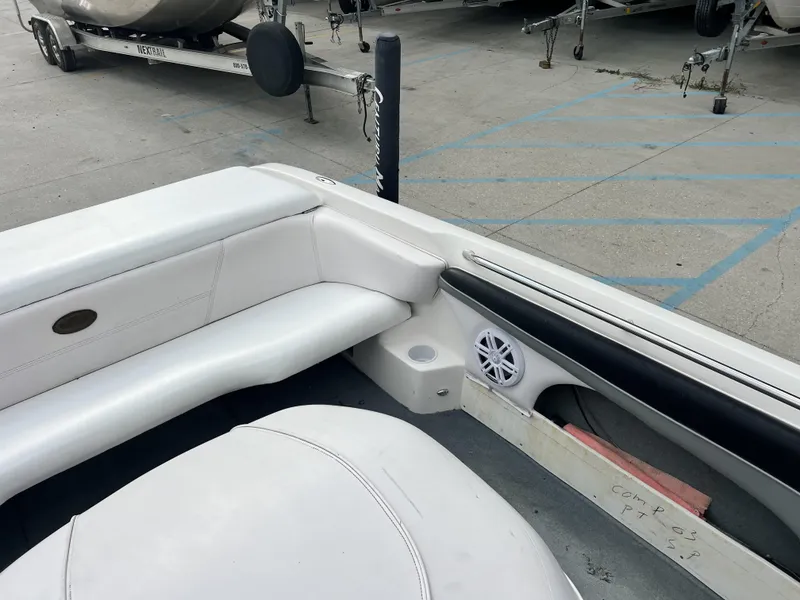 Slide: The Image of 2003 Supra Launch LTS boat interior with white seating and speaker, parked on concrete. - 15