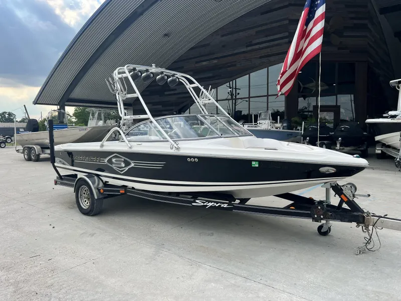 Slide: The Image of 2003 Supra Launch LTS boat on trailer, parked outside with American flag. - 7