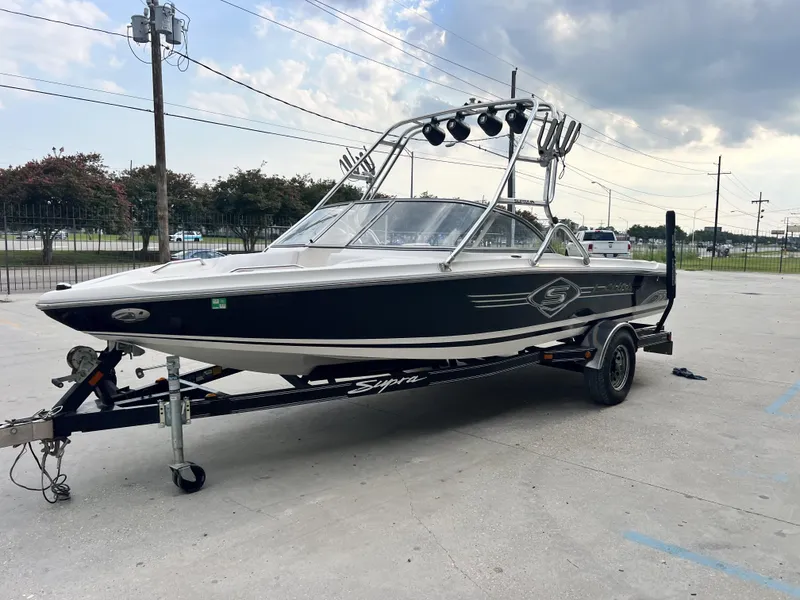 Slide: The Image of 2003 Supra Launch LTS boat on trailer, parked outdoors under cloudy sky. - 9