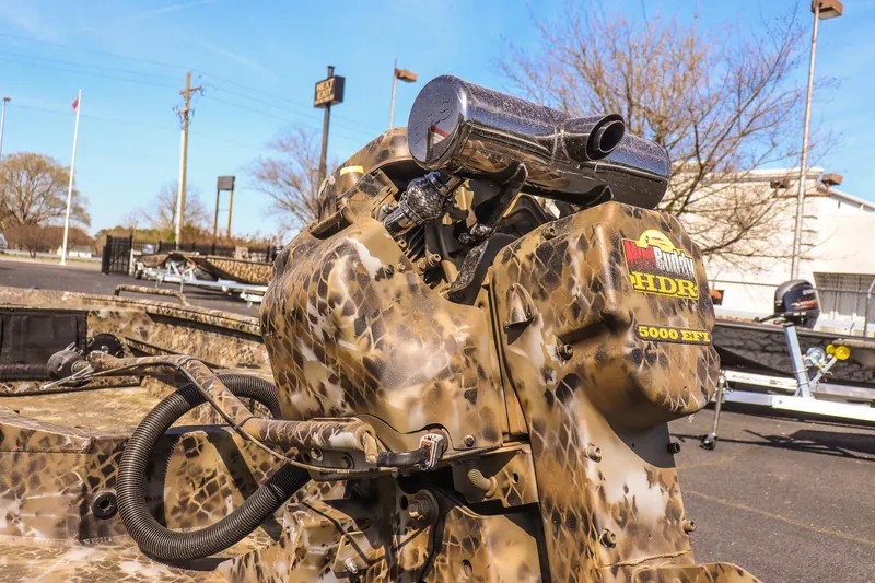 Slide: The Image of 2025 Excel 1751 F4 Shallow Water boat with camo-patterned motor in outdoor setting. - 7