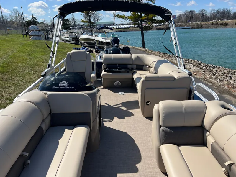 Slide: The Image of 2023 Sun Tracker Party Barge 20 DLX pontoon boat with beige seating, docked by a lake. - 12