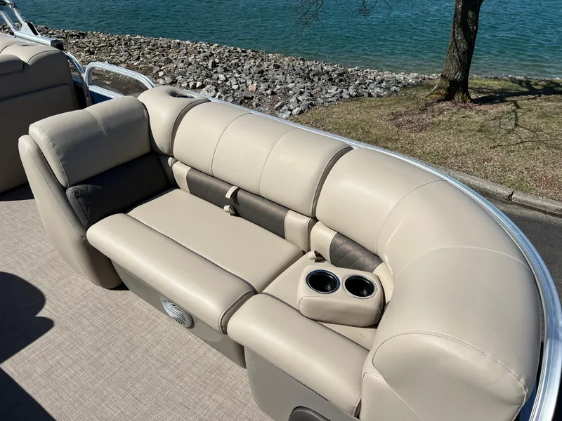 Slide: The Image of 2023 Sun Tracker Party Barge 20 DLX with beige seating, cup holders, near a lake. - 14