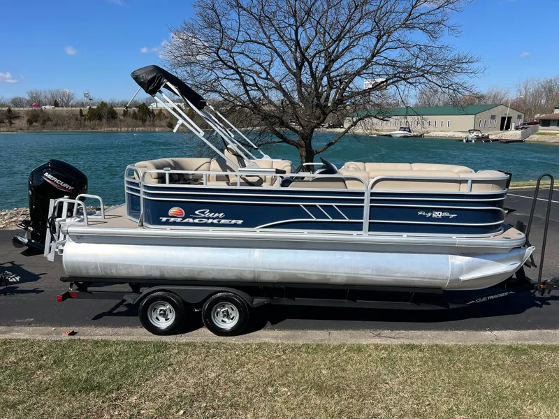Slide: The Image of 2023 Sun Tracker Party Barge 20 DLX pontoon boat on trailer by a lake. - 4