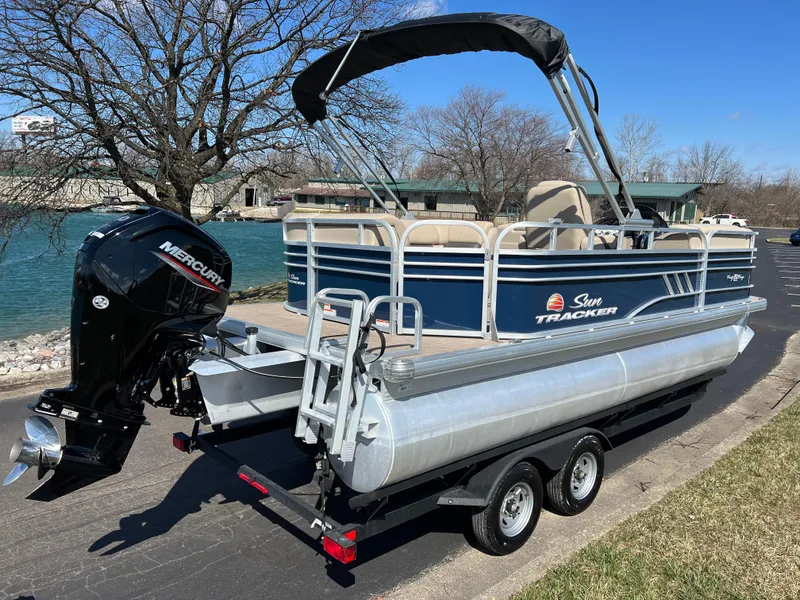 Slide: The Image of 2023 Sun Tracker Party Barge 20 DLX pontoon boat on trailer by a river. - 5