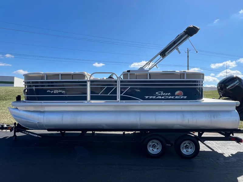 Slide: The Image of 2023 Sun Tracker Party Barge 20 DLX pontoon boat on trailer under clear blue sky. - 8