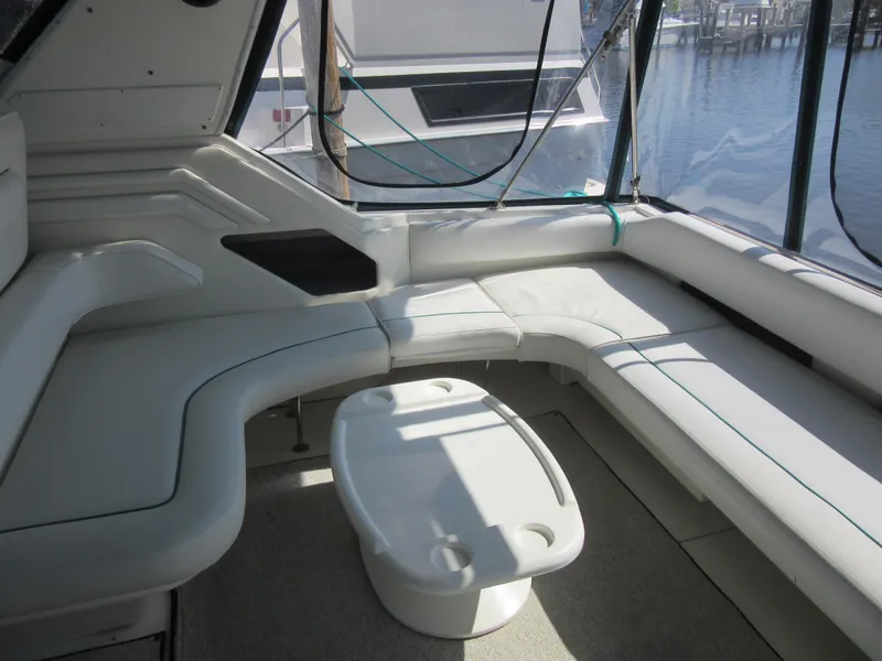 Slide: The Image of 1995 Sea Ray 400 Express Cruiser interior with white seating and table, docked by the water. - 15