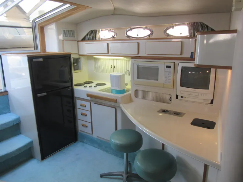 Slide: The Image of 1995 Sea Ray 400 Express Cruiser kitchen with appliances and seating. - 27