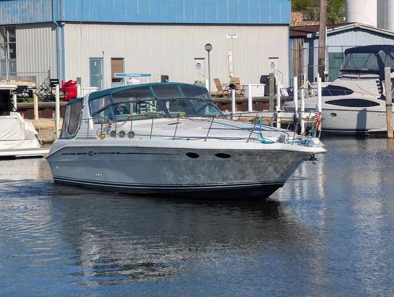 Slide: The Image of 1995 Sea Ray 400 Express Cruiser docked at marina, calm water, blue building background. - 3