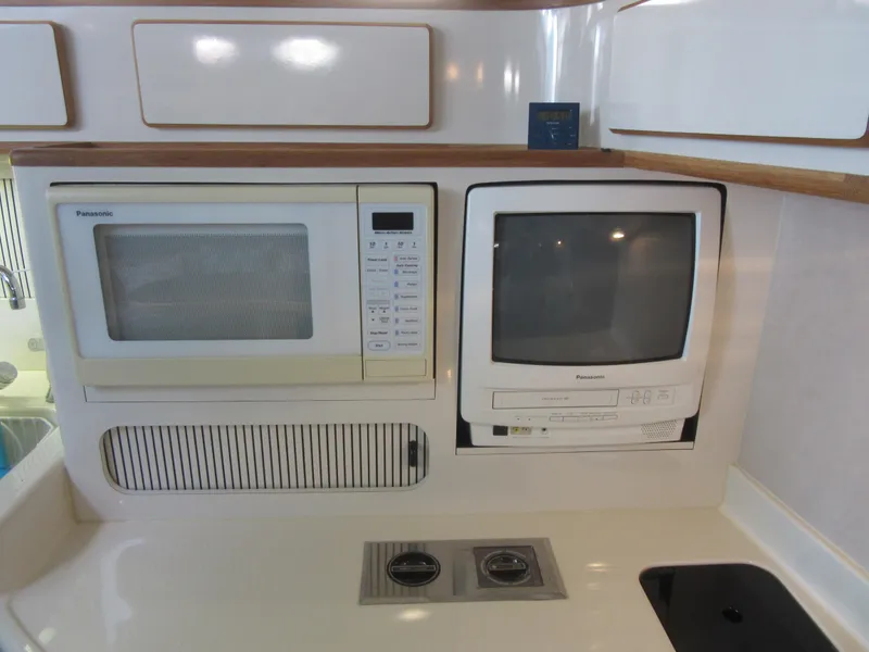 Slide: The Image of 1995 Sea Ray 400 Express Cruiser kitchen with microwave and TV. - 33