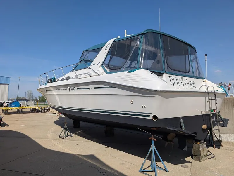 Slide: The Image of 1995 Sea Ray 400 Express Cruiser on dry dock, white hull, green canopy, sunny day. - 5