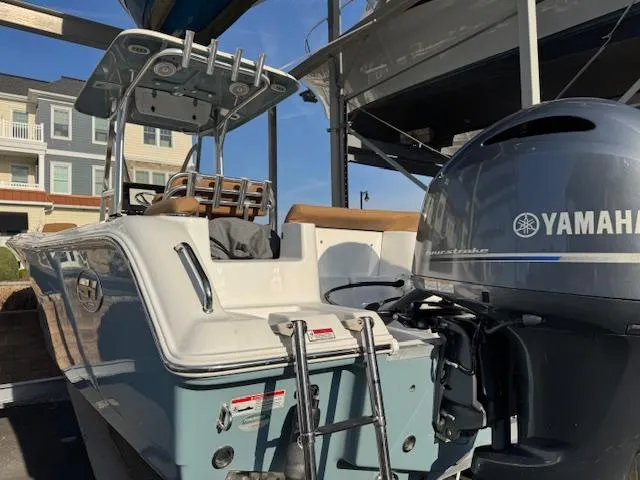 Slide: The Image of 2022 Sea Hunt Ultra 234 boat with Yamaha outboard motor, docked near residential buildings. - 2