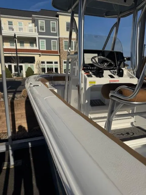 Slide: The Image of 2022 Sea Hunt Ultra 234 boat with modern console and seating, docked near residential buildings. - 6