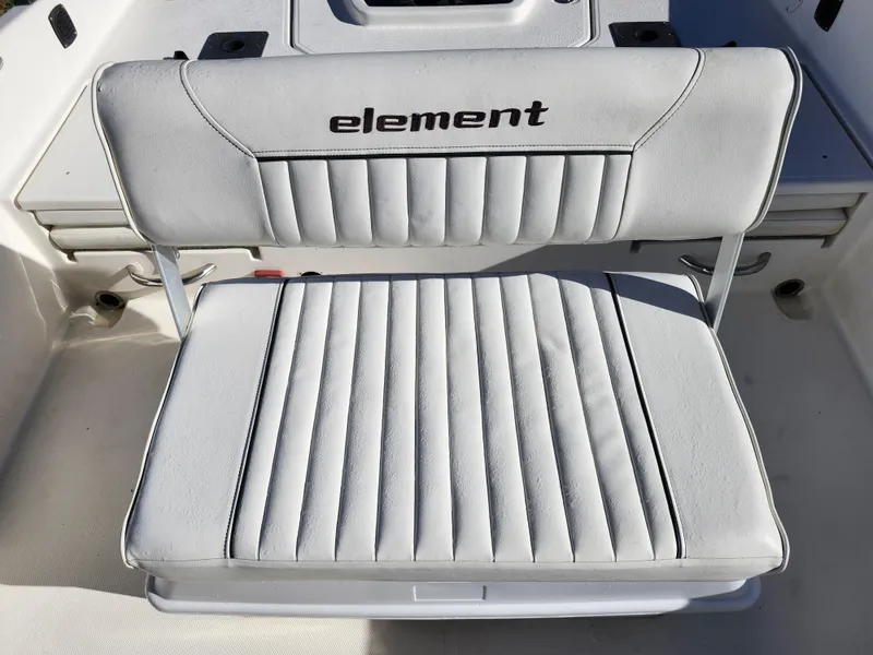 Slide: The Image of 2018 Bayliner Element F21 boat seat with "element" logo, white upholstery, and ribbed design. - 18