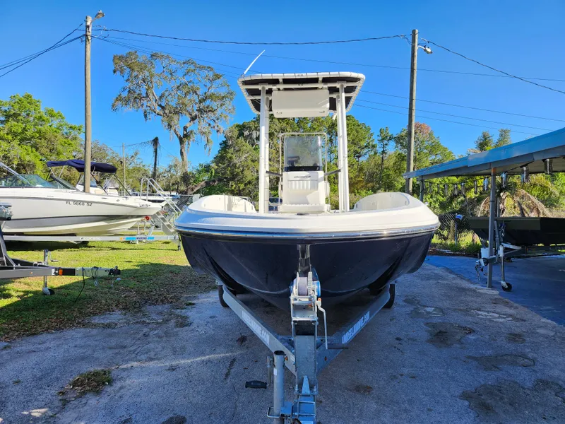 Slide: The Image of 2018 Bayliner Element F21 boat on trailer, parked outdoors under clear blue sky. - 2