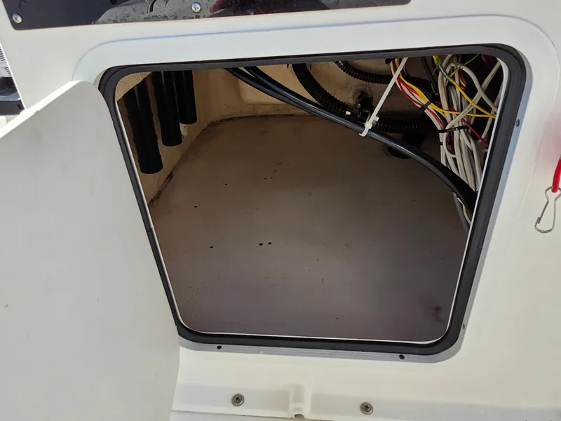 Slide: The Image of Open storage compartment on 2018 Bayliner Element F21 boat, showing wiring and interior space. - 29