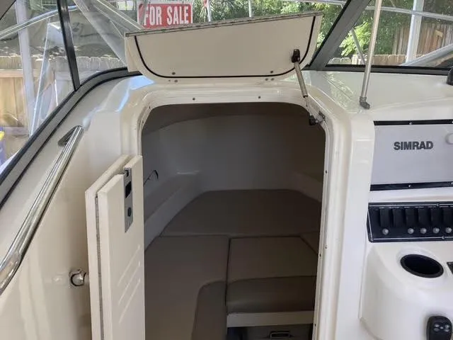 Slide: The Image of 2008 Boston Whaler 235 Conquest cabin interior with Simrad electronics, for sale sign visible. - 10