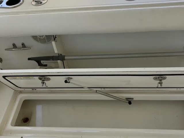 Slide: The Image of 2008 Boston Whaler 235 Conquest storage compartment with open hatch and rod holder. - 18