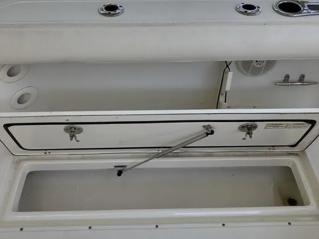 Slide: The Image of 2008 Boston Whaler 235 Conquest boat storage compartment with open hatch and rod holders. - 20