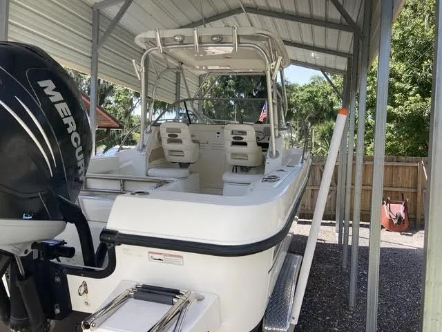 Slide: The Image of 2008 Boston Whaler 235 Conquest boat under a metal canopy, featuring a Mercury engine. - 32