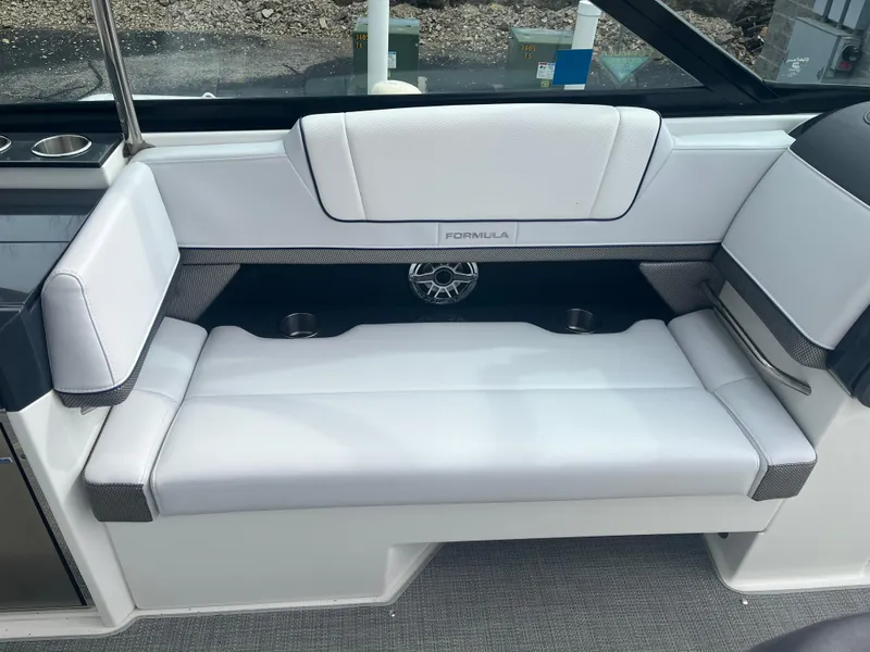 Slide: The Image of 2022 Formula 330 Crossover Bowrider I/O interior seating with white upholstery and speaker. - 8