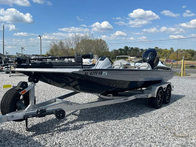 Slide: The Image of 2022 Xpress X19 Pro boat on trailer, parked on gravel, under a clear blue sky. - 2