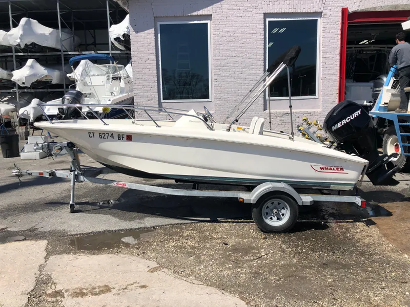 Slide: The Image of 2013 Boston Whaler 150 Super Sport boat on trailer, parked outdoors. - 13