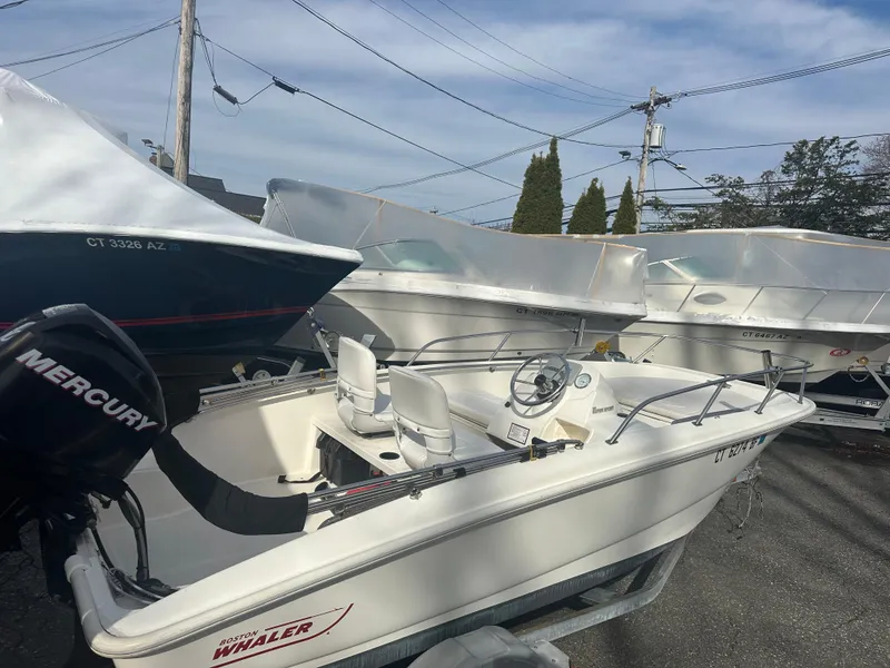 Slide: The Image of 2013 Boston Whaler 150 Super Sport boat with Mercury engine, parked outdoors. - 14