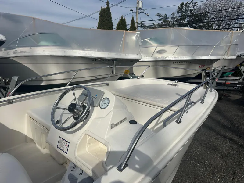 Slide: The Image of 2013 Boston Whaler 150 Super Sport boat, white interior, parked alongside other boats. - 15