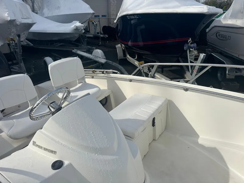 Slide: The Image of 2013 Boston Whaler 150 Super Sport boat interior with white seating and steering wheel. - 17