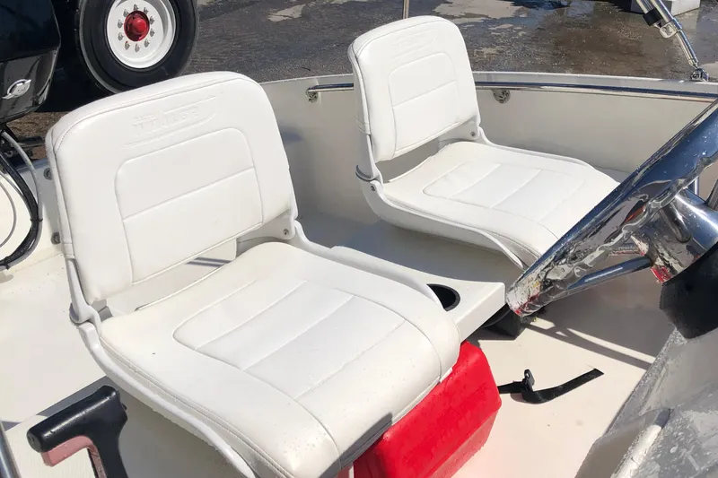 Slide: The Image of 2013 Boston Whaler 150 Super Sport boat interior with white seating and steering wheel. - 21