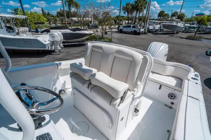 Slide: The Image of 2025 Sea Hunt Ultra 255 SE boat interior with helm and seating, parked outdoors. - 21
